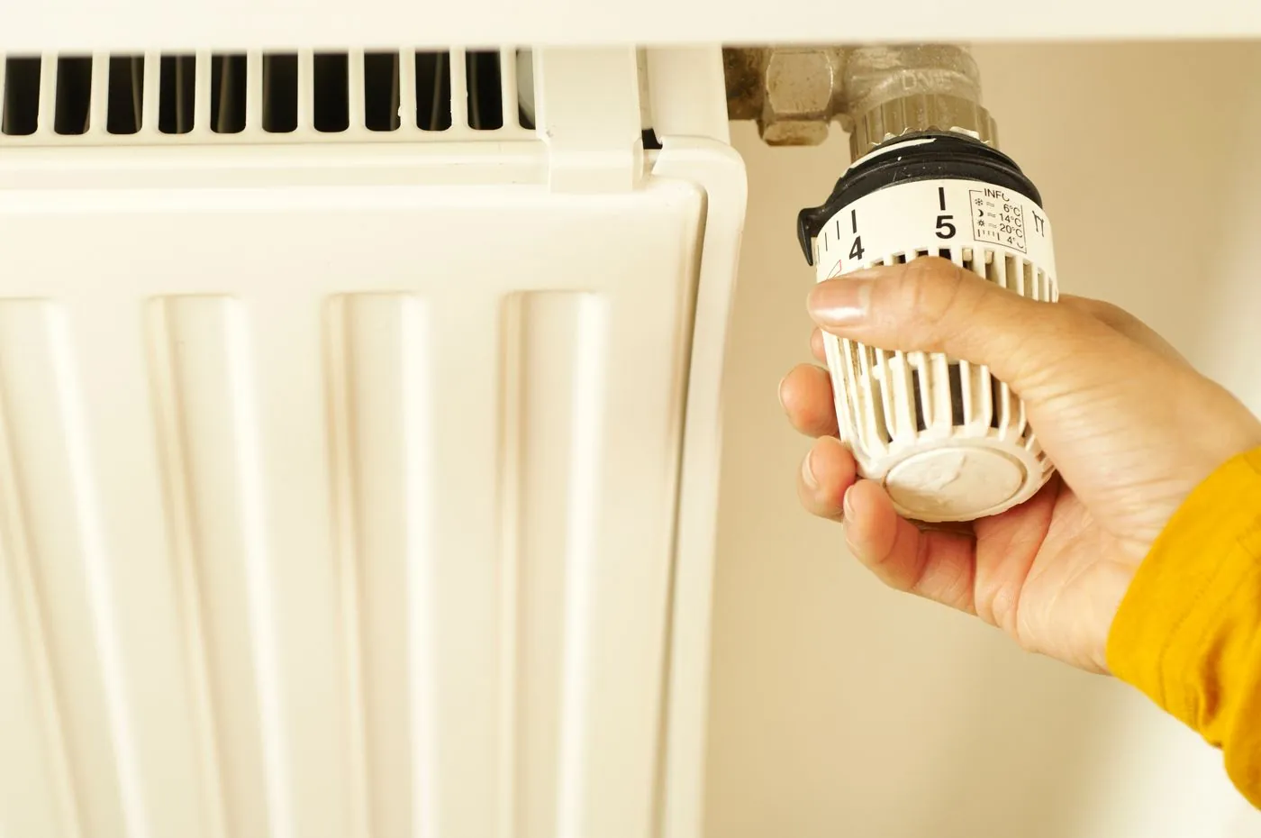 Ruka nastavuje termostatickou hlavici radiátoru