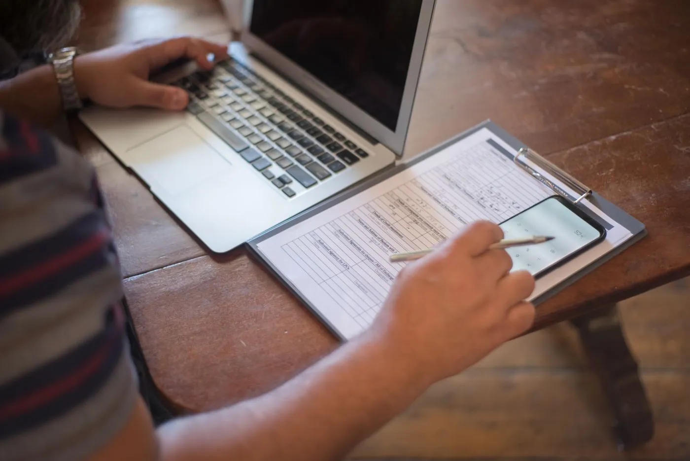 Vyplňování formuláře na klipovací desce vedle notebooku