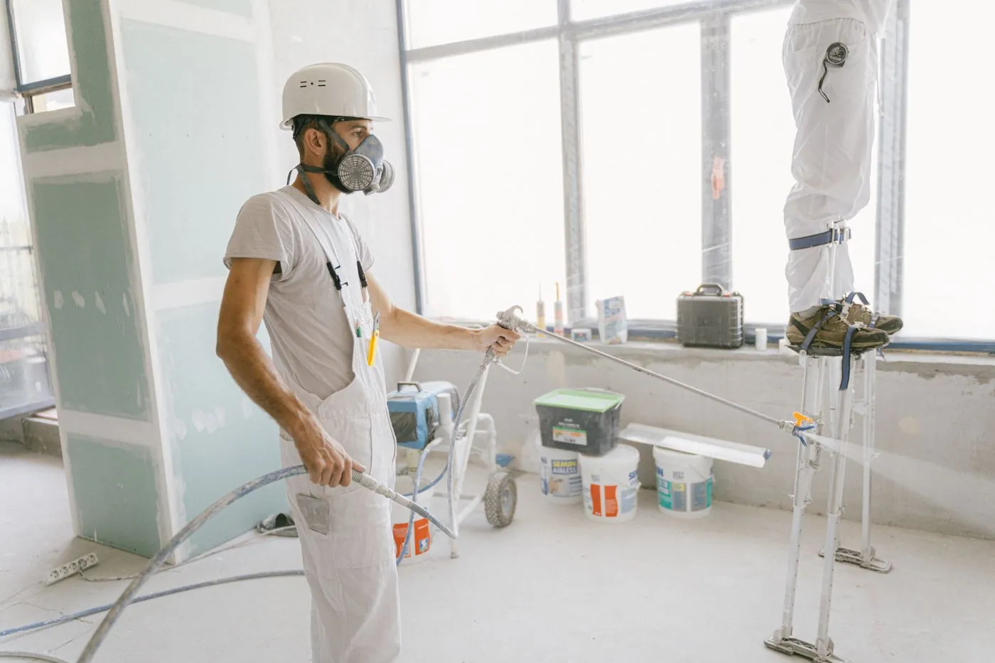 Dělník ve skafandru stříká izolaci v rekonstruovaném bytě